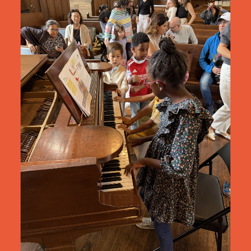 Children gathered around a grand piano