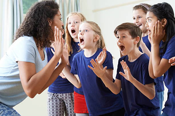 Instructor leading excited children in a vocal exercise
