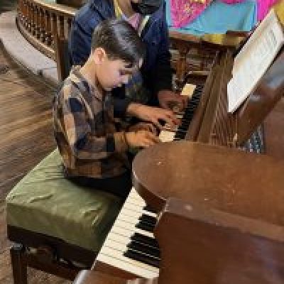 Young boy playing piano with teacher