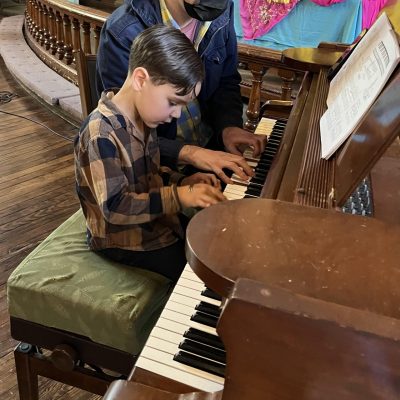 professor teach piano to the boy